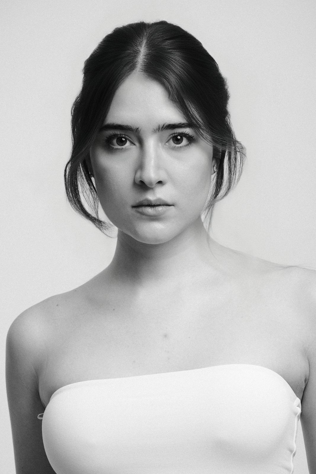 Paola Beatriz Miralles, black and white headshot, hair up, looking straight into the camera