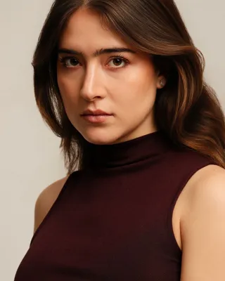Paola Beatriz Miralles, colour headshot, looking straight into the camera, wearing a dark burgundy sleeveless top