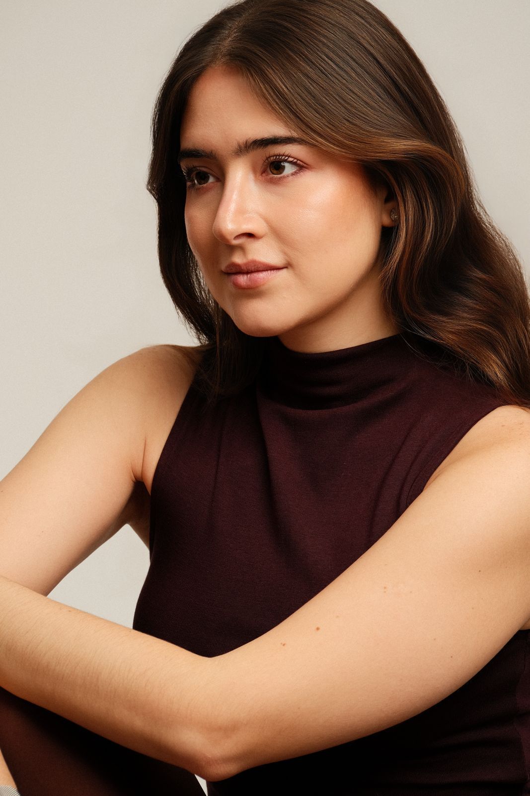 Paola Beatriz Miralles, colour headshot in three-quarter view with a slight smile, arms resting on her knee